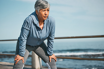 Image showing Senior, fitness and tired woman at the beach on break from training, workout or morning cardio run in nature. Sports, fatigue and elderly female runner stop to breathe on ocean workout or performance