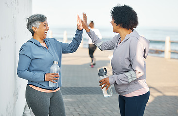 Image showing Fitness, happy and women high five by ocean for healthy lifestyle, wellness and cardio on promenade. Sports, friends and female people celebrate on boardwalk for exercise, training and workout goals