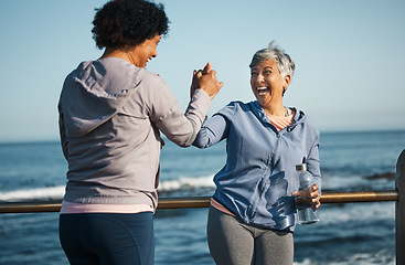 Image showing Fitness, high five and senior women friends at beach with exercise, celebration and excited in nature. Sport, people and elderly females with hands in support of wellness, training or success at sea