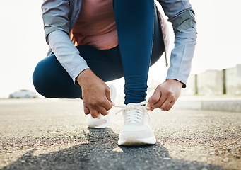 Image showing Fitness, closeup and woman tie shoes outdoor in the road for running workout in the city. Sports, health and zoom of female athlete tying her laces for cardio exercise for race or marathon training.