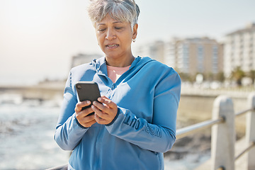Image showing News, phone and fitness with old woman at beach for running, workout and results. Network, communication and contact with female runner training in nature for technology, sports and mobile app