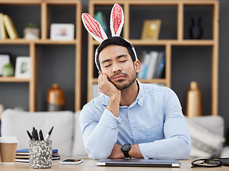 Image showing Tired, sleeping and a man for easter in an office with bunny ears for celebration or bored of a party. Stress, rabbit and a young Asian businessman with fatigue at a work desk with a problem