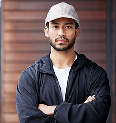 Image showing Courier man, outdoor portrait and arms crossed for service, delivery and ready for supply chain. Young logistics worker, serious face and city for customer satisfaction, commerce and distribution job