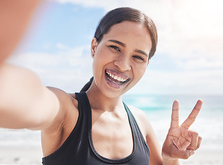 Image showing Fitness, selfie and woman at beach with peace hands for running, sports or exercise in nature. Portrait, happy and lady health and wellness influencer smile for social media, blog or profile picture