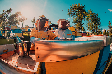 Image showing Beekeepers checking honey on the beehive frame in the field. Small business owners on apiary. Natural healthy food produceris working with bees and beehives on the apiary.