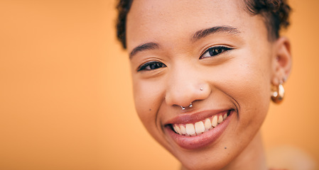 Image showing Happy, woman and face closeup in studio with smile and confidence feeling cute. Orange background, young portrait and African female person with trendy, piercing and student fashion with gen z glow