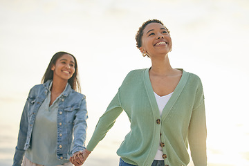 Image showing Love, ocean and happy lesbian couple holding hands, walking together and sunset holiday adventure. Lgbt women, bonding and relax on beach vacation with romantic date, pride and smile on nature travel
