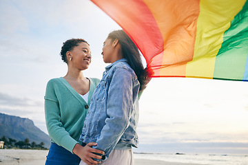 Image showing Pride, flag and lesbian couple at the beach for travel, freedom and bond, care and happy in nature together. Rainbow, love and women on ocean vacation embrace lgbt, partner or gay, date or acceptance