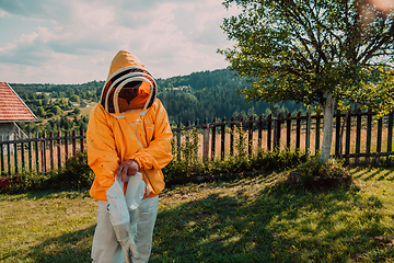 Image showing Beekeeper put on a protective beekeeping suit and preparing to enter the apiary