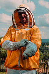 Image showing Beekeeper put on a protective beekeeping suit and preparing to enter the apiary