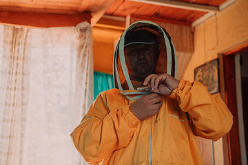 Image showing Beekeeper put on a protective beekeeping suit and preparing to enter the apiary