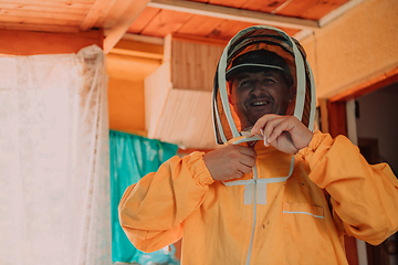 Image showing Beekeeper put on a protective beekeeping suit and preparing to enter the apiary