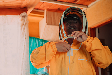 Image showing Beekeeper put on a protective beekeeping suit and preparing to enter the apiary