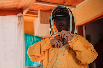 Image showing Beekeeper put on a protective beekeeping suit and preparing to enter the apiary