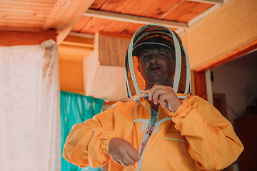 Image showing Beekeeper put on a protective beekeeping suit and preparing to enter the apiary