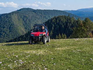 Image showing A man driving a quad ATV motorcycle through beautiful meadow landscapes