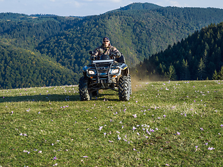 Image showing A man driving a quad ATV motorcycle through beautiful meadow landscapes