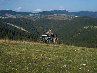 Image showing A man driving a quad ATV motorcycle through beautiful meadow landscapes