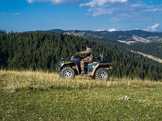 Image showing A man driving a quad ATV motorcycle through beautiful meadow landscapes