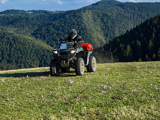 Image showing A man driving a quad ATV motorcycle through beautiful meadow landscapes