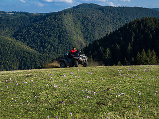 Image showing A man driving a quad ATV motorcycle through beautiful meadow landscapes