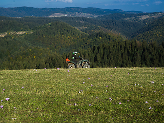 Image showing A man driving a quad ATV motorcycle through beautiful meadow landscapes