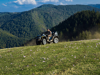 Image showing A man driving a quad ATV motorcycle through beautiful meadow landscapes