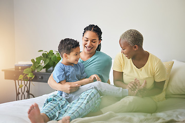 Image showing Playing, gay family and morning in bed or home bedroom for security, quality time and love. Adoption, lesbian or LGBTQ women or parents and happy kid together to wake up with tickle, care or fun game