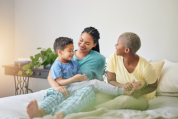 Image showing Gay family, morning and playing on bed in home bedroom for bonding, quality time and love. Adoption, lesbian or LGBTQ women or interracial parents and a happy kid to wake up with fun, care and laugh