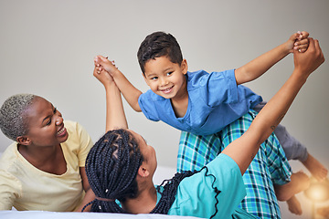 Image showing Child, gay family and playing on bed in home bedroom for security, quality time and love. Adoption, lesbian or LGBTQ women or parents lift a happy kid to wake up with care, fun game and a smile