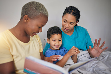 Image showing Reading, LGBT family and child with a book in bed for knowledge, education and learning. Adoption, lesbian or gay women or parents and foster kid together in home bedroom with story for quality time