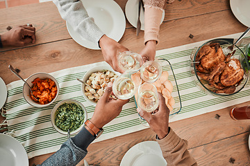 Image showing Wine, food and toast with hands of family at dining table for party, celebration and holiday from above. Lunch, cheers and success with closeup of people and at home for event, support and dinner