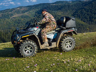 Image showing A man driving a quad ATV motorcycle through beautiful meadow landscapes