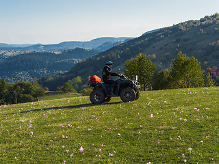 Image showing A man driving a quad ATV motorcycle through beautiful meadow landscapes