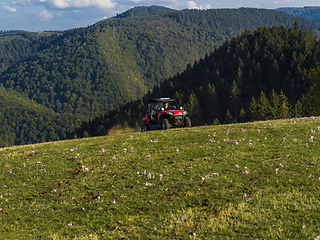 Image showing A man driving a quad ATV motorcycle through beautiful meadow landscapes