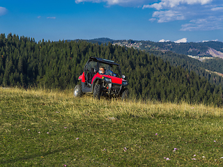 Image showing A man driving a quad ATV motorcycle through beautiful meadow landscapes