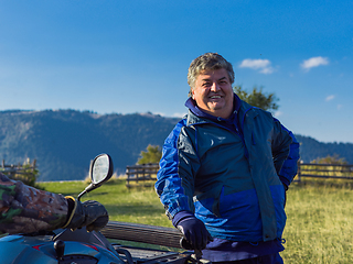 Image showing A man in a forest posing next to a quad and preparing for ride