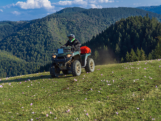 Image showing A man driving a quad ATV motorcycle through beautiful meadow landscapes