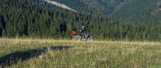 Image showing A man driving a quad ATV motorcycle through beautiful meadow landscapes