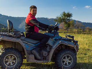 Image showing A man driving a quad ATV motorcycle through beautiful meadow landscapes