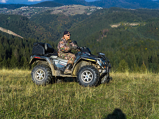 Image showing A man driving a quad ATV motorcycle through beautiful meadow landscapes