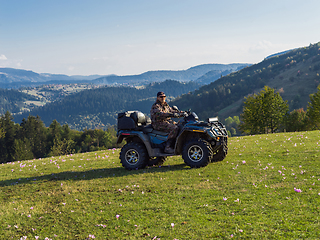 Image showing A man driving a quad ATV motorcycle through beautiful meadow landscapes