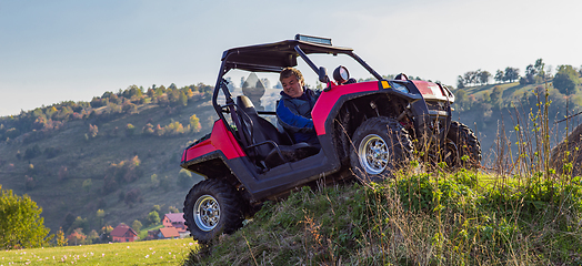 Image showing A man driving a quad ATV motorcycle through beautiful meadow landscapes