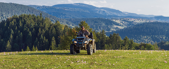 Image showing A man driving a quad ATV motorcycle through beautiful meadow landscapes