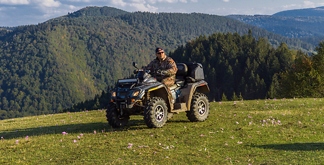 Image showing A man driving a quad ATV motorcycle through beautiful meadow landscapes