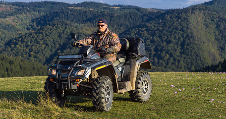 Image showing A man driving a quad ATV motorcycle through beautiful meadow landscapes