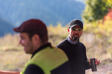 Image showing A man in motorcycle gear with a cap and sunglasses holds a water bottle