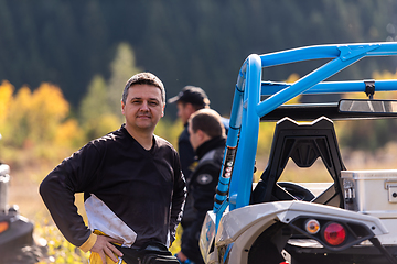 Image showing A man in a forest posing next to a quad and preparing for ride