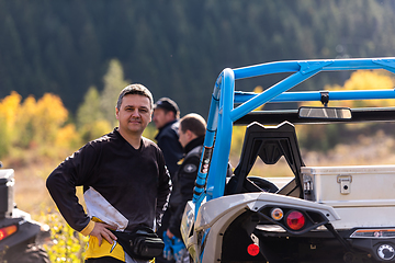 Image showing A man in a forest posing next to a quad and preparing for ride