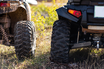 Image showing Close-up tail view of ATV quad bike on dirt country road. Dirty wheel of AWD all-terrain vehicle. Travel and adventure concept.